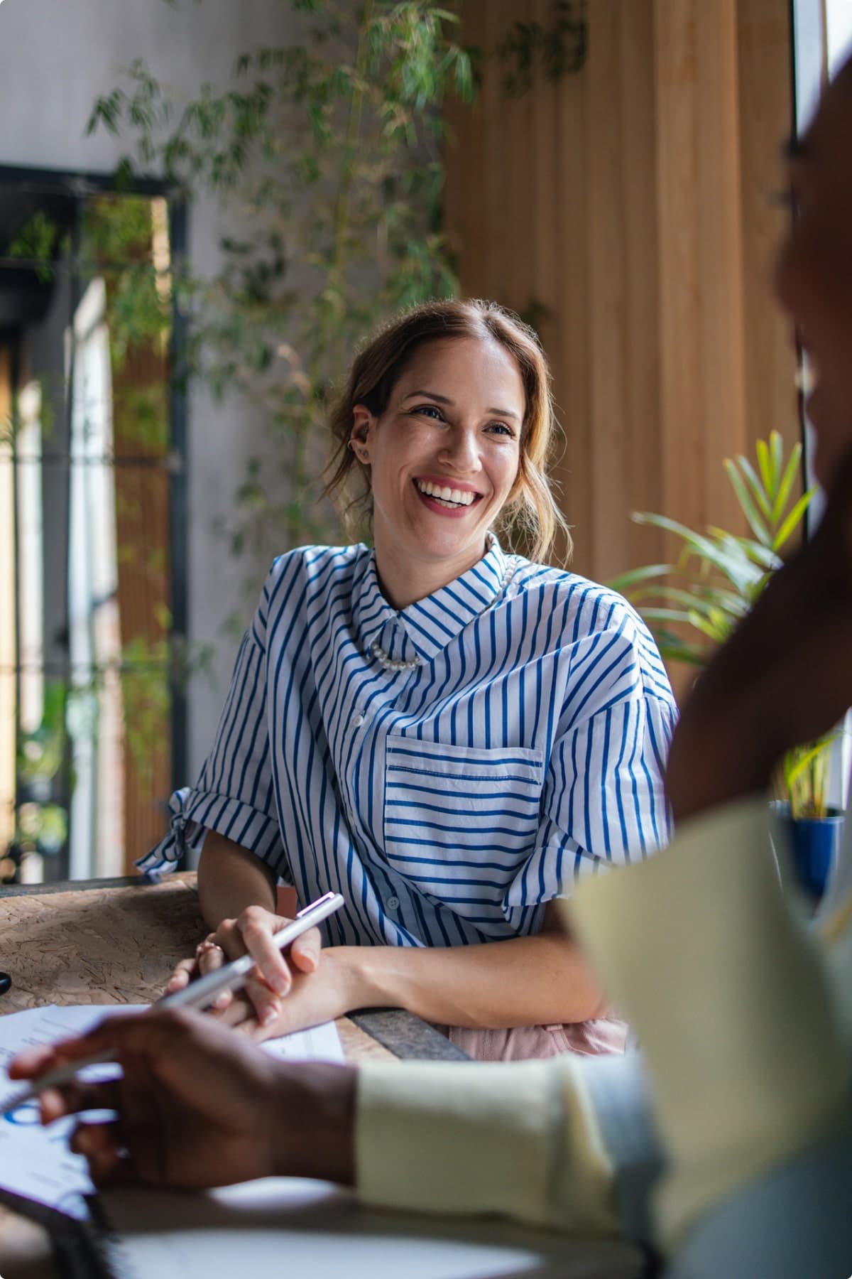 Portrait of a Beautiful Smiling Businesswoman Sitting at the Table and Talking to a Colleague