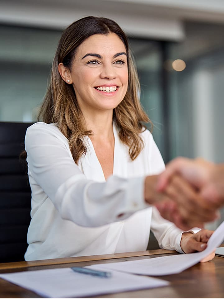 Happy mid aged business woman manager handshaking at office meeting