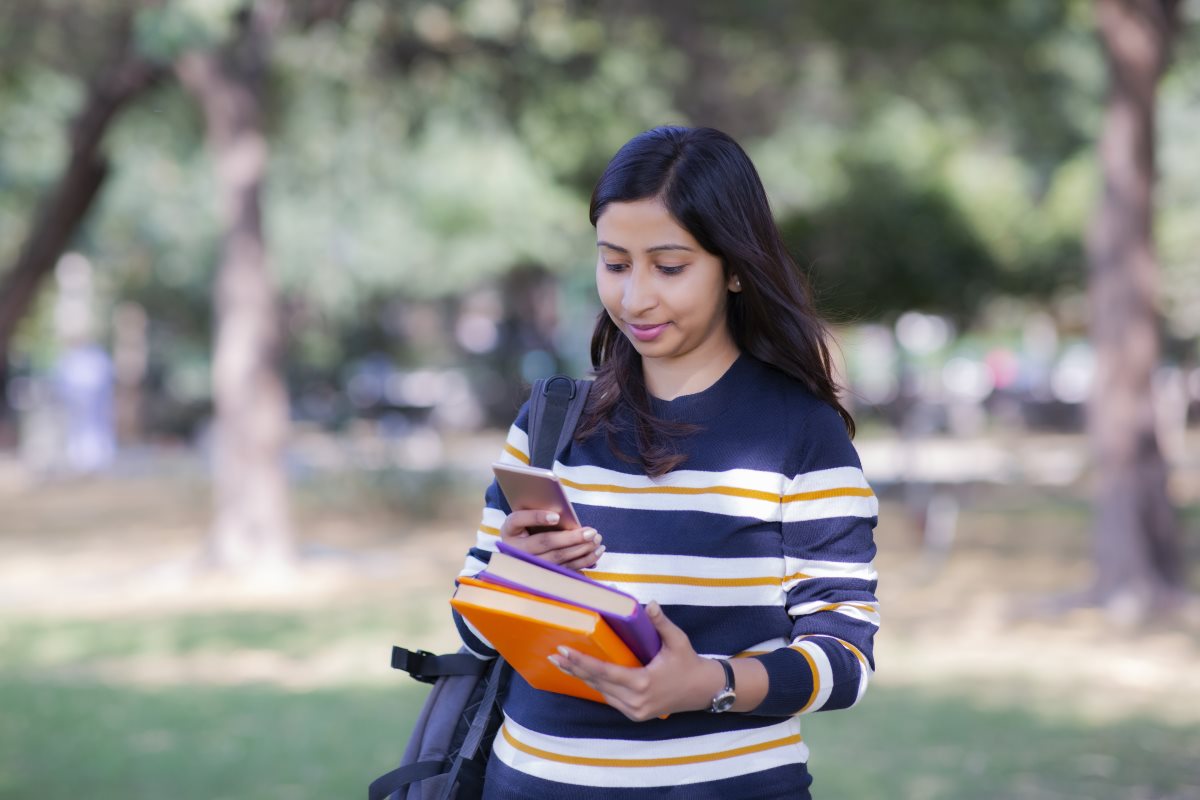 International student smiling at her phone.