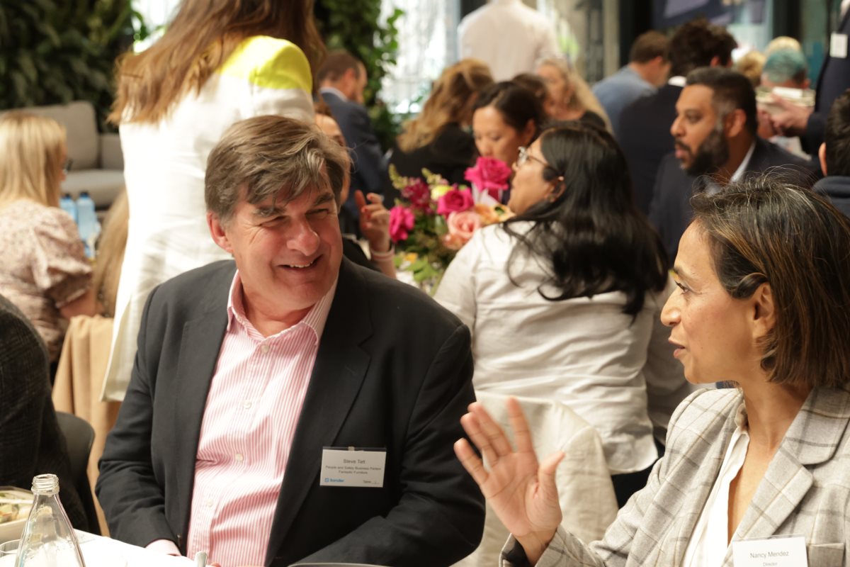 People sitting down smiling and talking at a formal event.