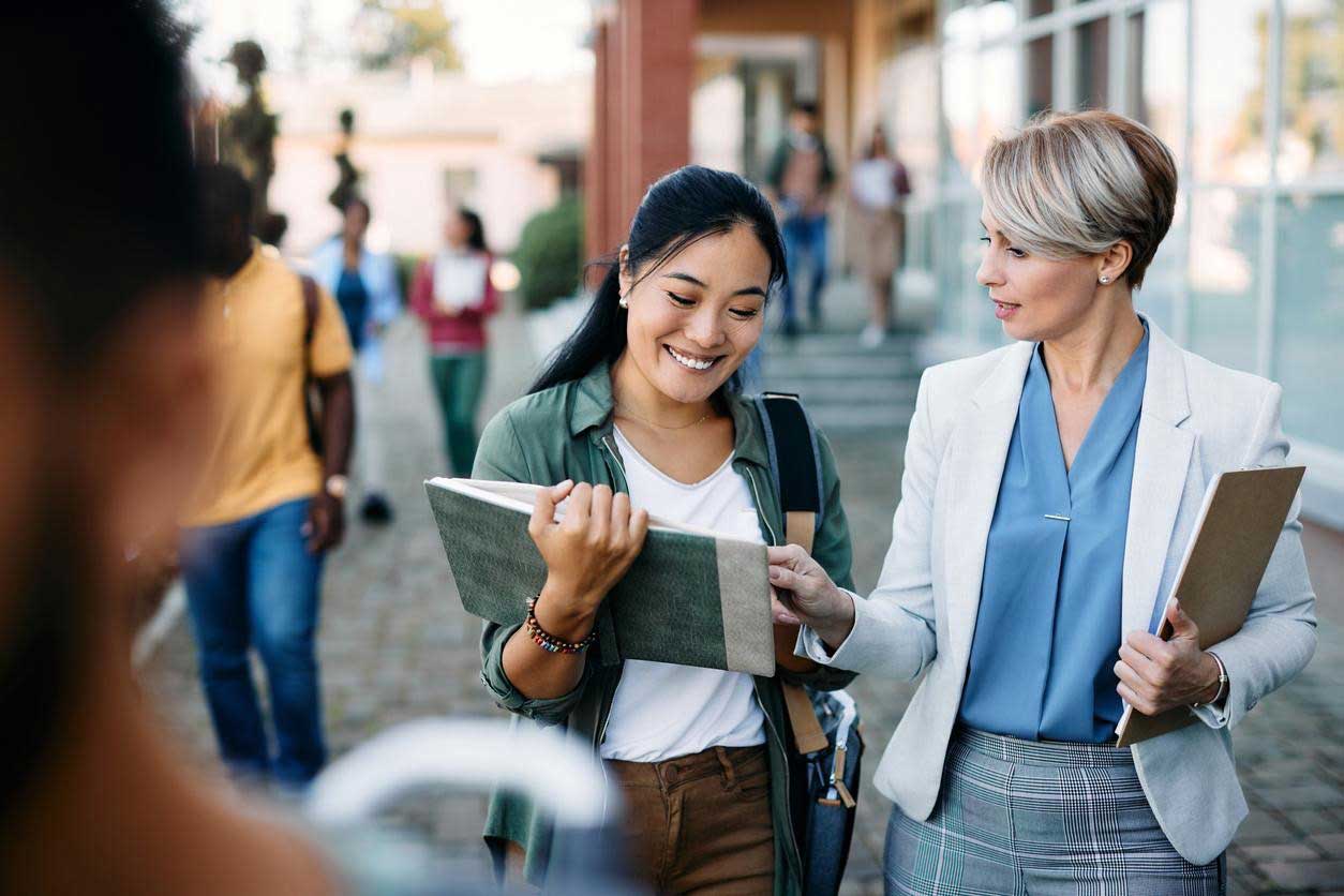 Asian student excitedly conversing with teacher.