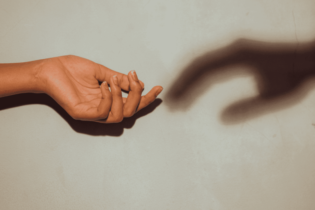 A hand and its shadow, as if the shadow was reaching out to touch the real hand