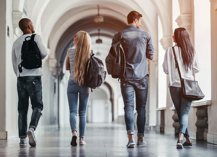 Students wearing backpacks walking the halls of a school.