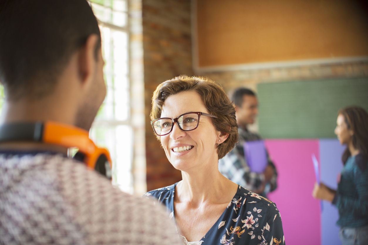Woman smiling at young man in a classroom environment.