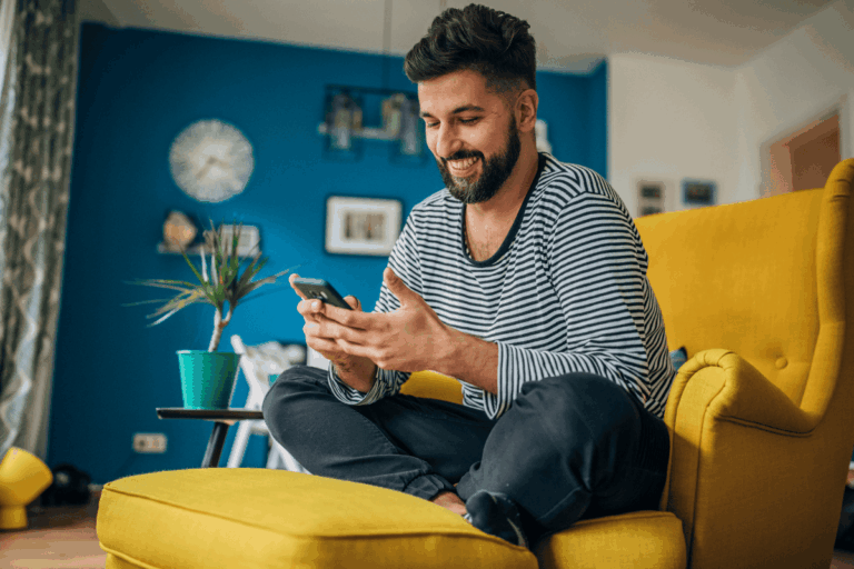 Man at home looking at his phone and smiling