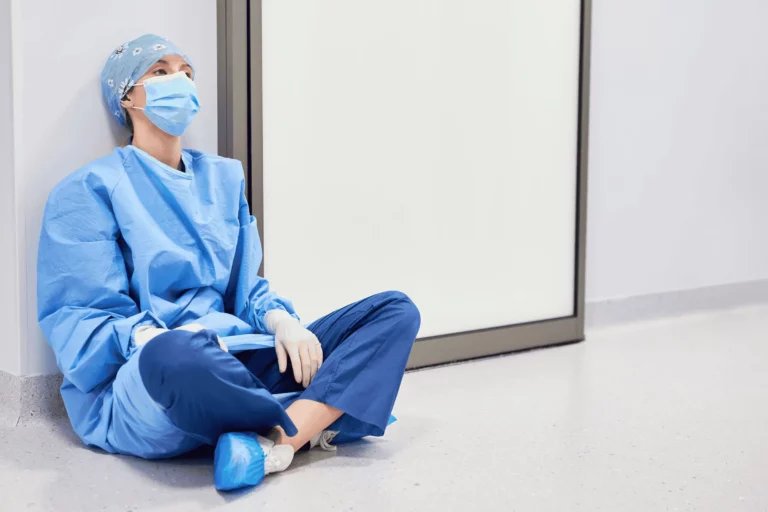 Doctor looking exhausted sitting on a hospital hallway