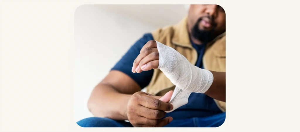 Factory worker applying bandage to his left hand