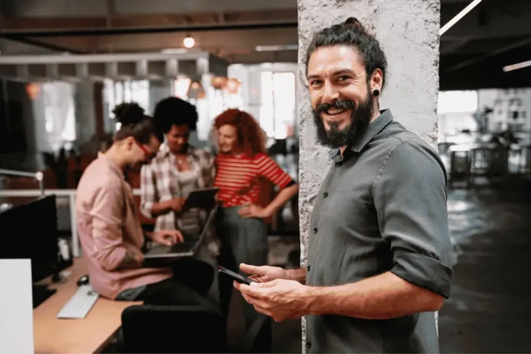 Happy man holding a phone at an informal office