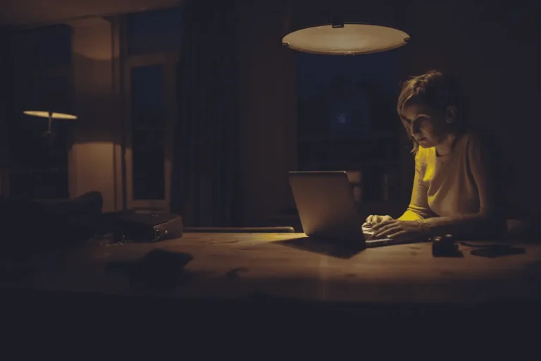 Woman working on her laptop in a dark room