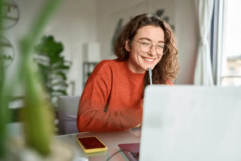 Woman happily working at her desk with her laptop
