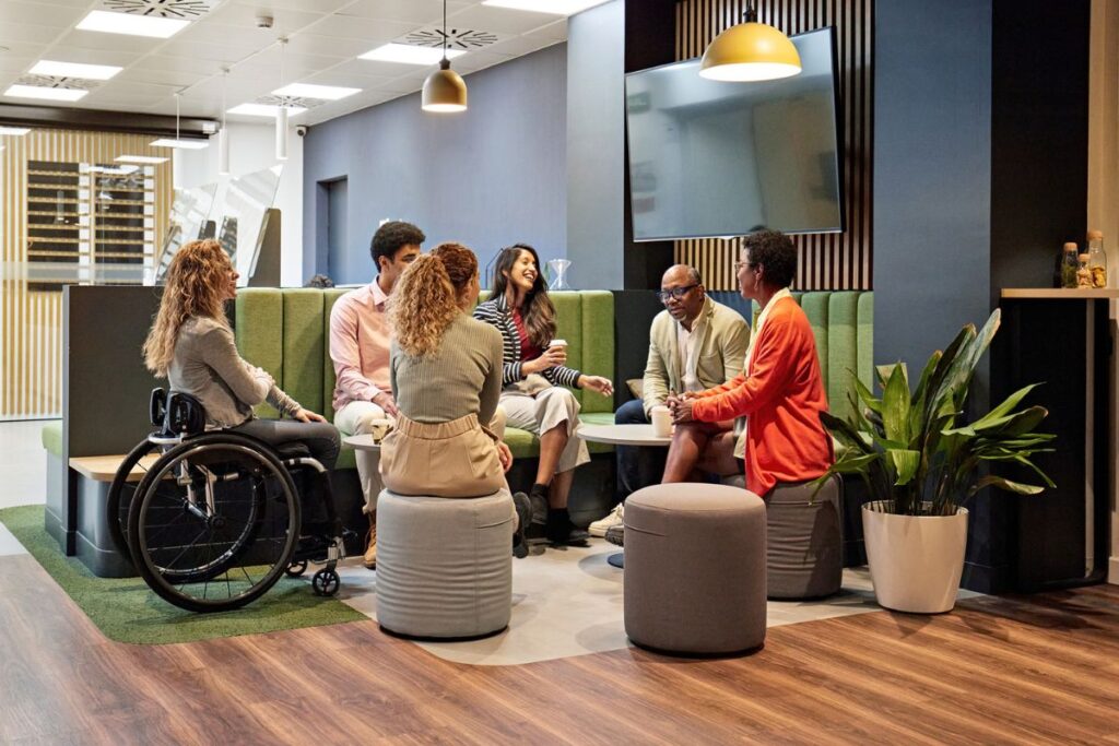 a group of diverse employees sit together and talk in an office