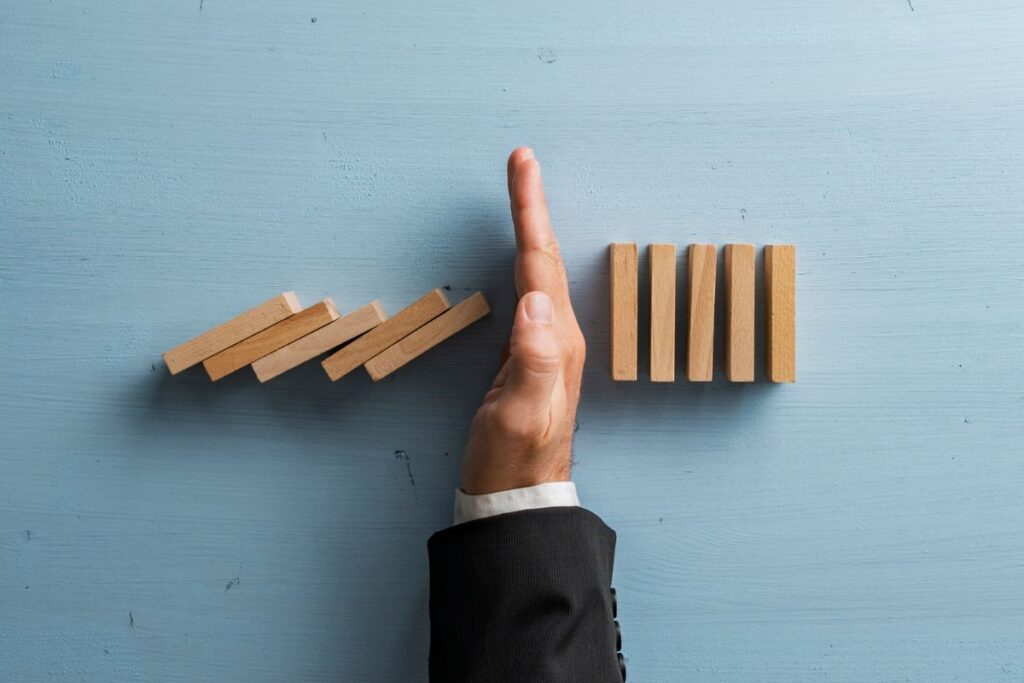 man stops blocks from falling with his hand on a blue table