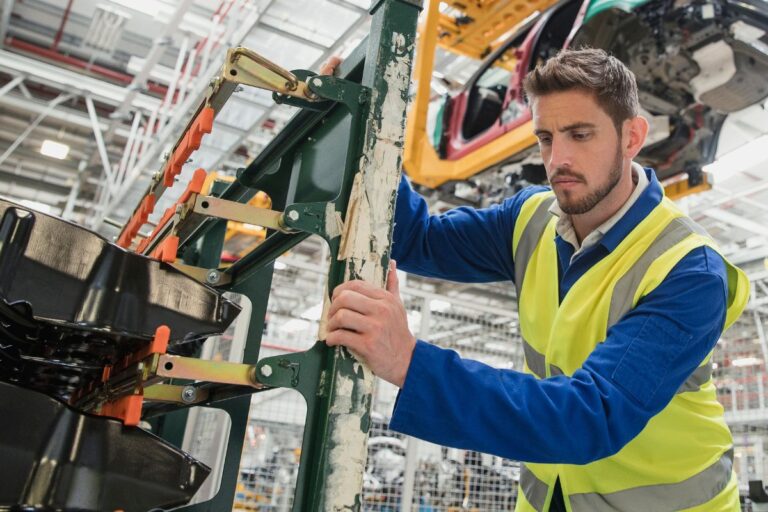 young man with a beard works in a factory alone