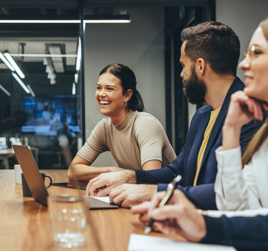 A few people smiling in a conference room