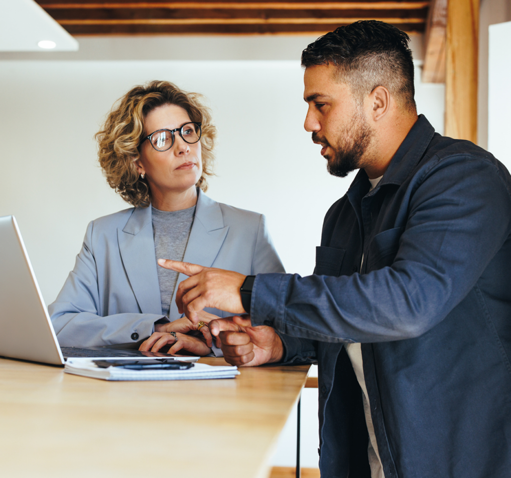 Co workers talking while working on a laptop