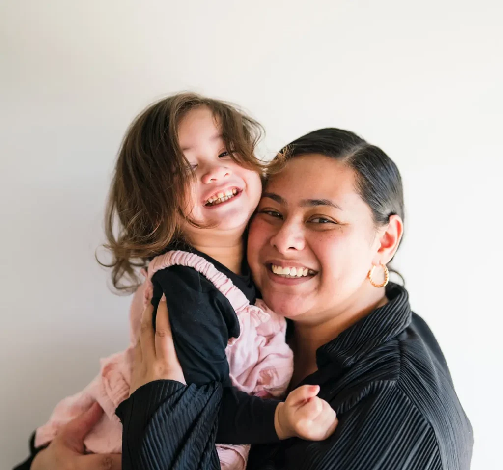 Mum hugging her toddler, both smiling
